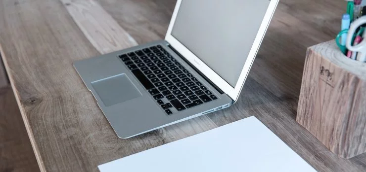 Laptop i list papira pored njega.
