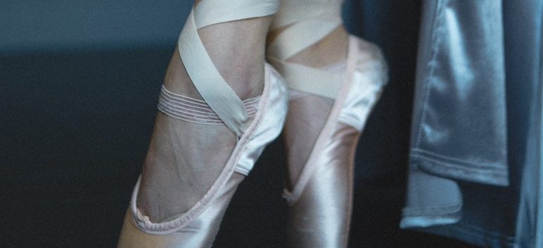 Woman putting on ballet shoes.